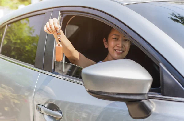 Vrouw met een autosleutel in haar hand terwijl ze in haar auto zat. — Stockfoto