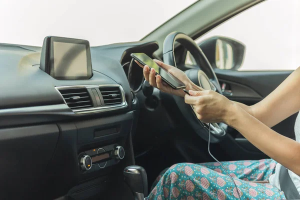 Autofahrerin lädt ihr Smartphone im Auto auf. — Stockfoto