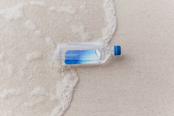 Bottle of drinking water on beach near the sea. — Stock Photo, Image