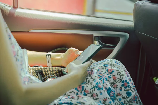 Casual vrouw in taxi auto met behulp van smartphone. — Stockfoto