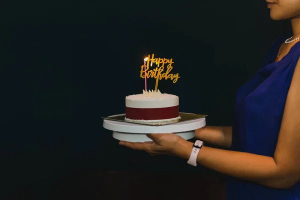 Frau hält Geburtstagstorte mit Kerze und Geburtstagsteller. — Stockfoto