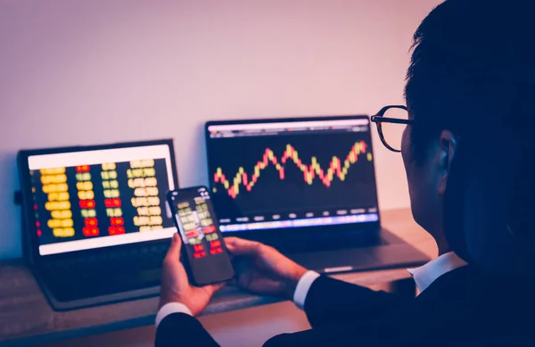 Empresario que utiliza el teléfono celular con el gráfico estadístico del análisis del mercado de valores en la pantalla del ordenador portátil y la tecnología. — Foto de Stock