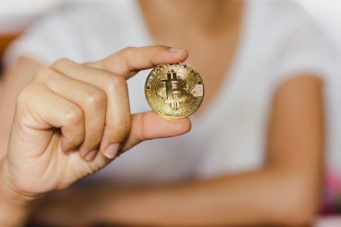 Successful woman holding gold bitcoin in her hand.