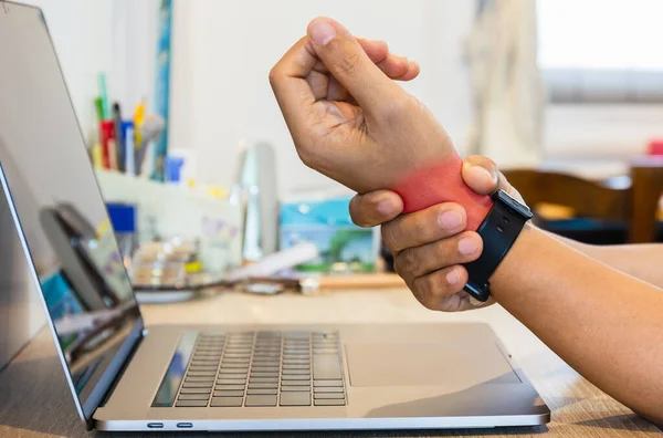 Man voelde zijn pols pijn terwijl woking met laptop thuis. — Stockfoto