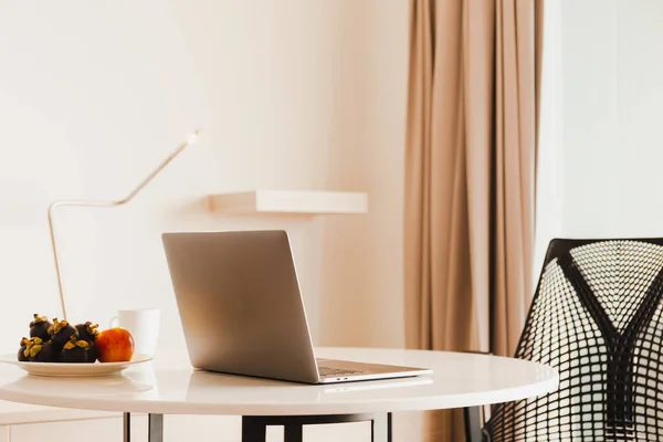 Portátil abierto en mesa de mármol en la sala de estar con frutas frescas y taza de café. — Foto de Stock