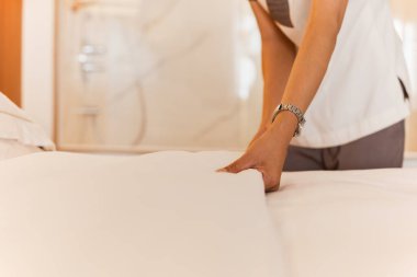 Otel odasında yatağı yapan kadın hizmetçinin eli.
