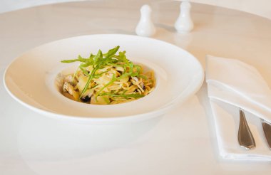 Beyaz tabakta mantarlı krema soslu makarna.