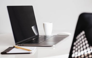 Boş ekran laptopunu ve kahve fincanını diğer ofis malzemeleriyle yapıştır.