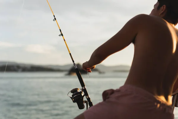 Fishing rod wheel closeup, man fishing with a beautiful sunset