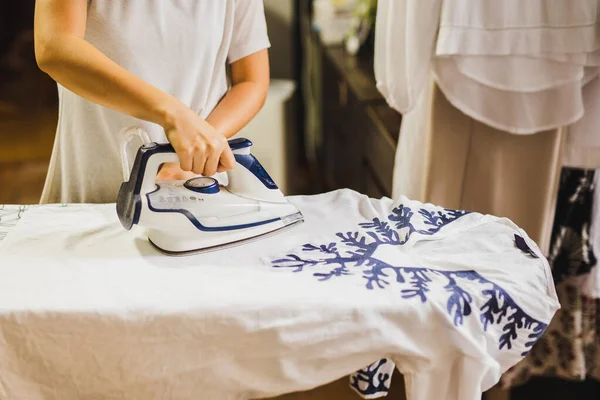 Caucasian housewife ironing on ironing board after laundry