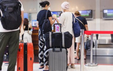 Two woman passengers with face mask check in at the airport