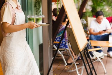 Önlüklü garson kafedeki müşteriye buzlu matcha latte ikram ediyor. Yüksek kalite fotoğraf