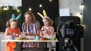 İki kız ve anne Paskalya yumurtalarını boyuyor ve kameraya video kaydediyor..