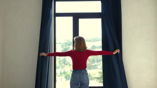 Chica abre cortinas azules y ventana — Vídeo de stock