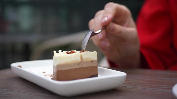 Primo piano di una donna taglia con un cucchiaio un pezzo di torta al cioccolato. — Video Stock