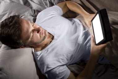 adam yatakta bir tablet ile