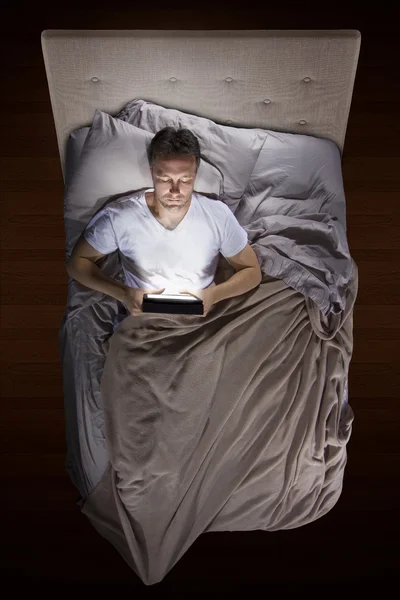 Homem na cama com um tablet — Fotografia de Stock