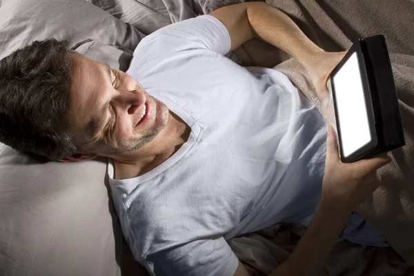 Mann mit Tablette im Bett — Stockfoto