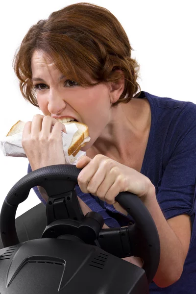 Woman eating a sandwich while driving — Stock Photo, Image