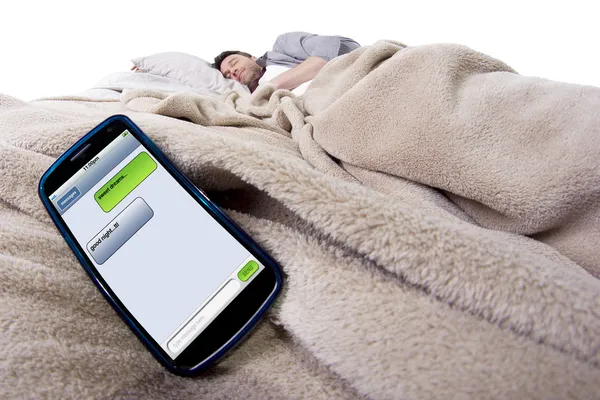 Scherm van de mobiele telefoon toont tekstberichten terwijl man is in bed — Stockfoto