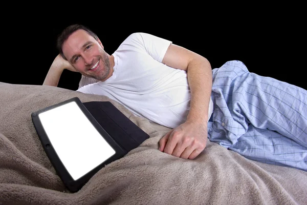 Мужчина читает на таблетке перед сном — стоковое фото