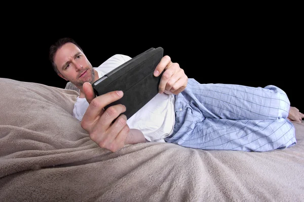 Leitura masculina em um comprimido antes de ir dormir — Fotografia de Stock