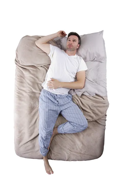 Sleep deprived man on a bed — Stock Photo, Image