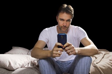 Yatak odasında cep telefonu kullanan adam