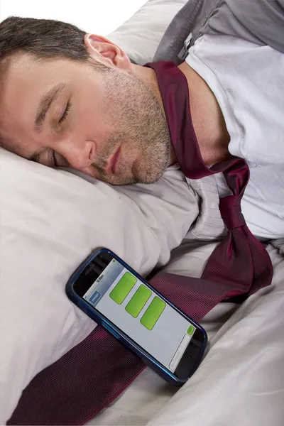 Человек спит и получает текстовые сообщения с работы — стоковое фото