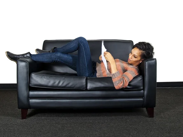 ソファの上を読んでいる女性 — ストック写真