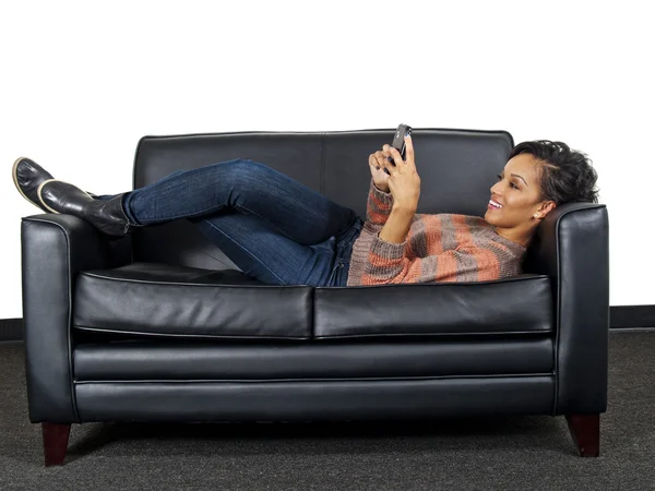 Vrouw met behulp van smartphone op sofa — Stockfoto