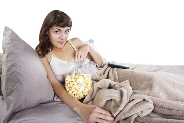 Teenager sledování filmů v posteli s popcorn — Stock fotografie