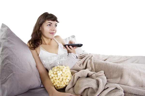 Adolescente assistindo filmes na cama com pipocas — Fotografia de Stock