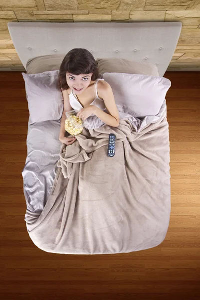 Teenager schaut Filme im Bett mit Popcorn — Stockfoto