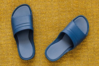 Hardal sarısı halıda klasik mavi parmak arası terlikler.