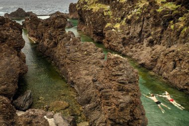 Porto Moniz 'in eski doğal havuzlarında iki yüzücü (Madeira, Portekiz)
