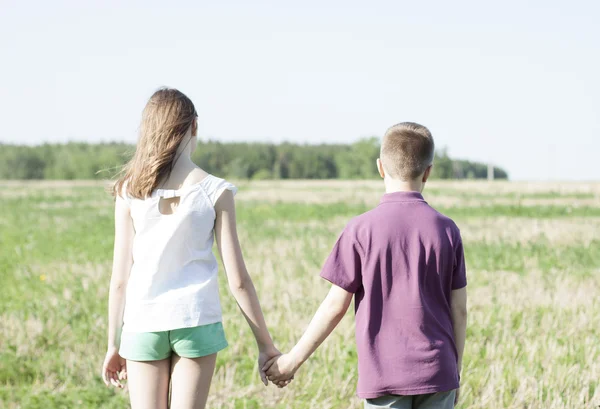 Niño sosteniendo la mano de chica en el campo verde — Foto de Stock