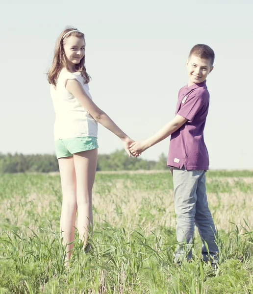 Мальчик держит девушку за руку на зеленом поле — стоковое фото