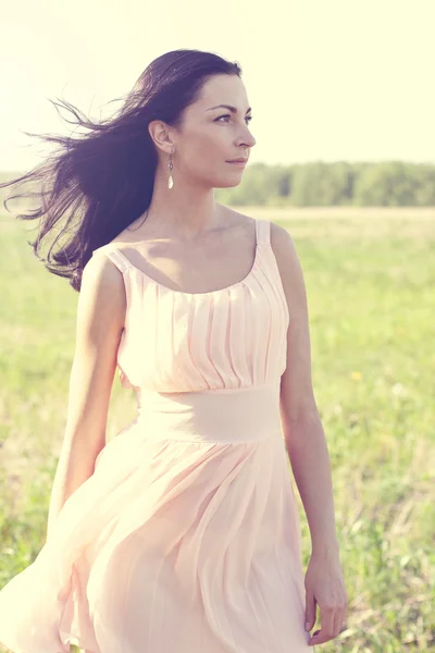 Женщина в розовом платье в поле — стоковое фото