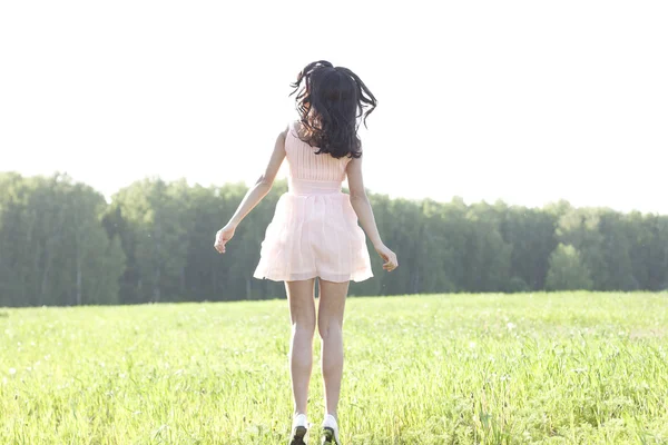 Menina em um vestido pulando em um campo — Fotografia de Stock