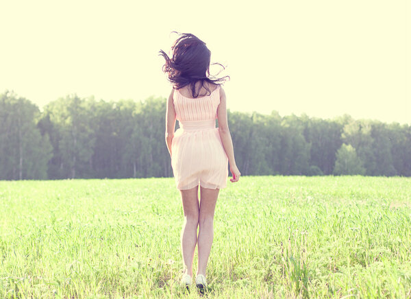 Girl in a dress jumping in a field