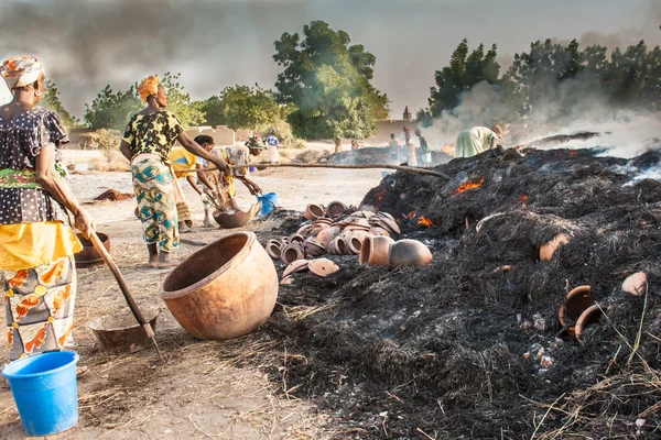 As mulheres assam as panelas de barro em um grande fogo . — Fotografia de Stock