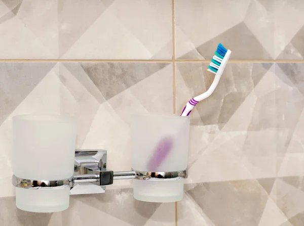 Brosses à dents dans une tasse en verre dans la salle de bain. — Photo