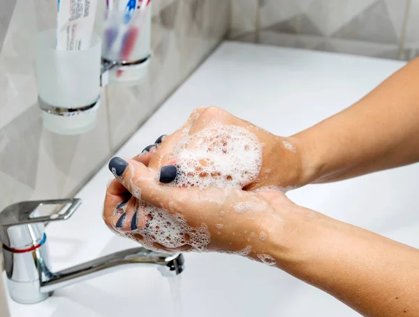 Une femme se lave les mains avec du savon liquide et de l'eau propre. Lavez-vous les mains pour les garder propres. — Photo