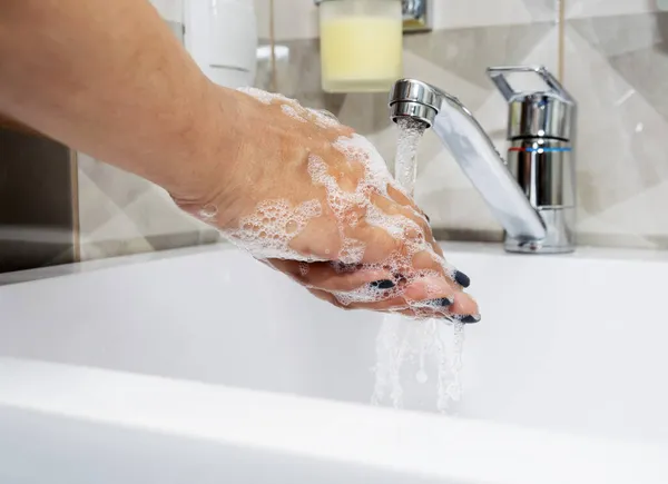 Une femme se lave les mains avec du savon liquide et de l'eau propre. Lavez-vous les mains pour les garder propres. — Photo