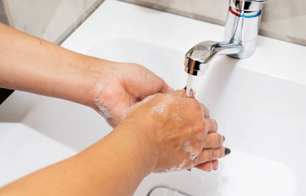 Une femme se lave les mains avec du savon liquide et de l'eau propre. Lavez-vous les mains pour les garder propres. — Photo