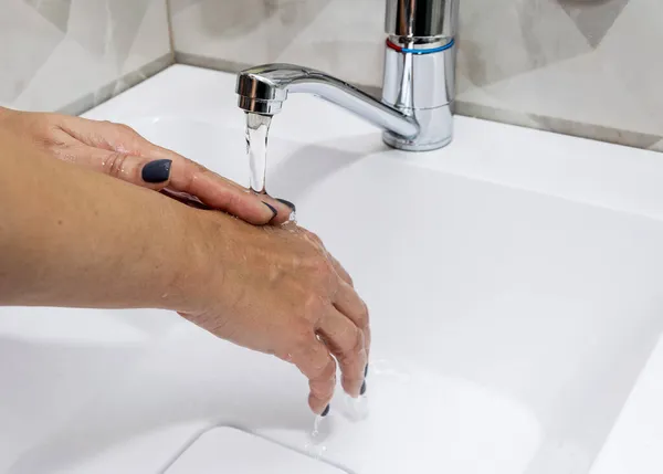 Μια γυναίκα πλένει τα χέρια της με υγρό σαπούνι και καθαρό νερό. Πλύνε τα χέρια σου για να μείνουν καθαρά.. — Φωτογραφία Αρχείου