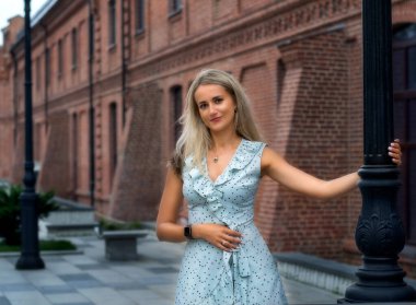 Genç, mutlu bir kız güneşli bir günde sokakta yürüyor..