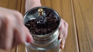 Man grinding coffee beans using a manual hand coffee grinder