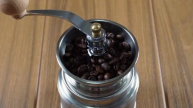 Carefully pouring coffee beans into a manual hand coffee grinder